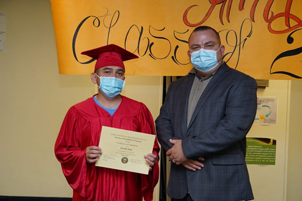 California Rehabilitation Center Warden Glen E. Pratt with Integrated Substance Use Disorder Treatment (ISUDT) Cognitive Behavioral Interventions (CBI) Life Skills graduate and class Valedictorian Erwin Soto. On June 25, California Rehabilitation Center recognized 13 students in a graduation ceremony of the CBI Life Skills class, including Soto, making them the first graduates under the new model. (Photo courtesy California Department of Corrections and Rehabilitation)